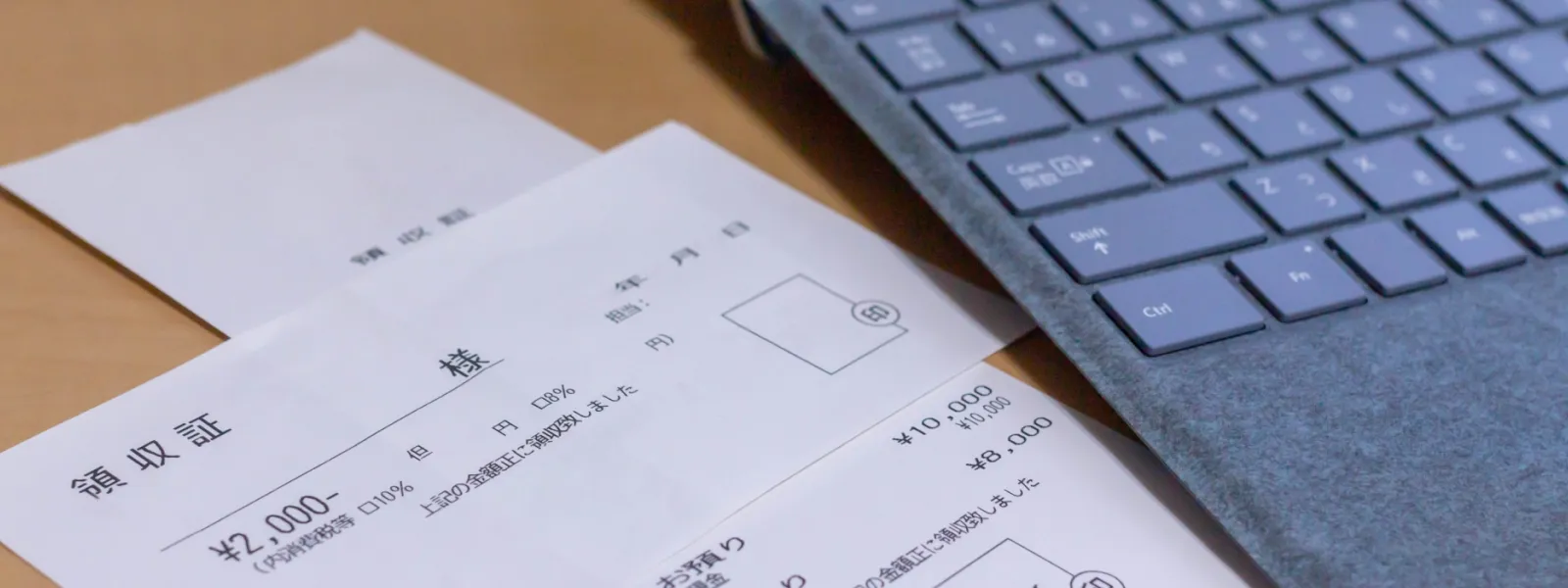 パソコンと領収書が机に置かれている様子