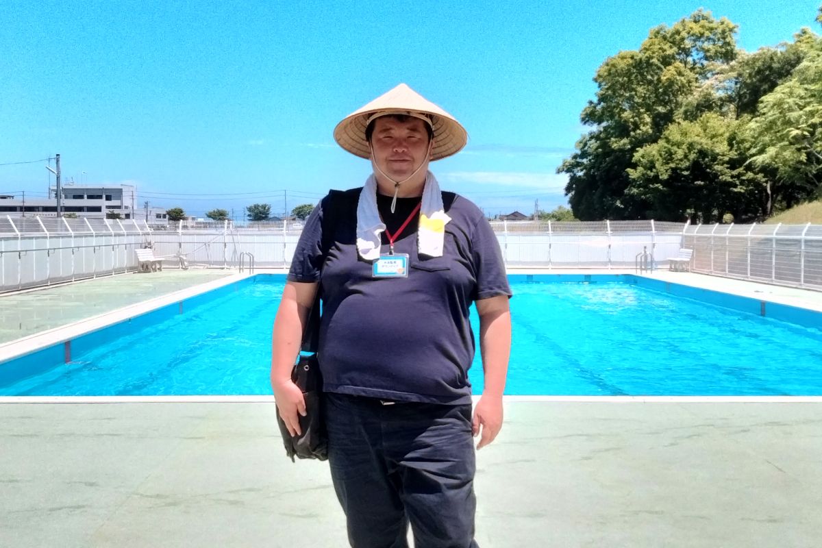 プールサイドで麦わら帽子を被って立っている幸田健太