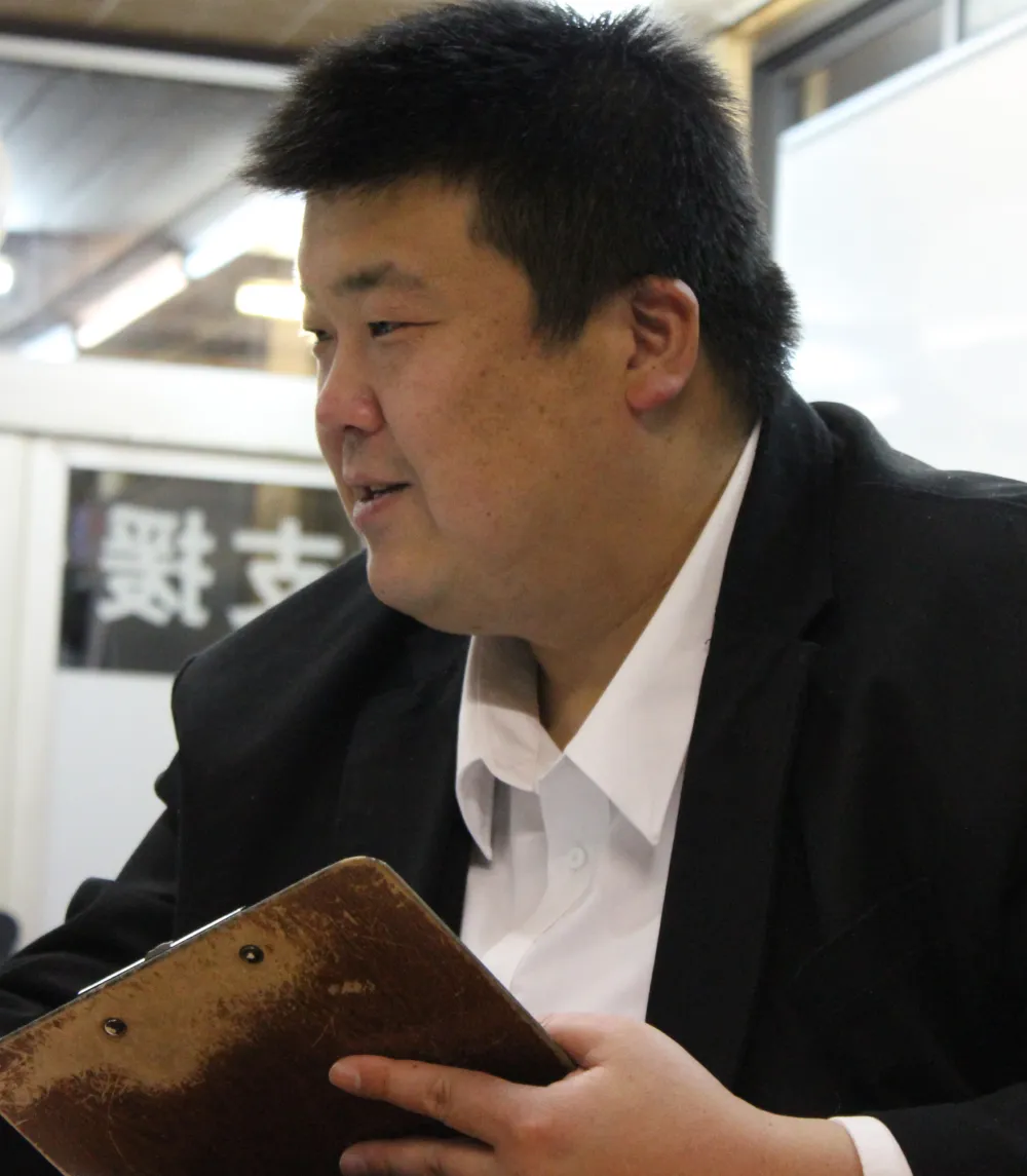 幸田健太がバインダーを持って学習指導をしている様子